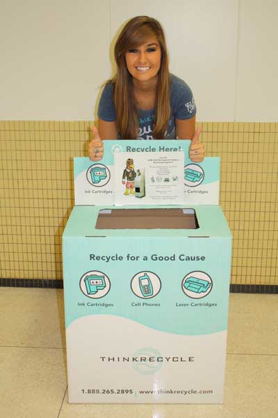 Freshman Anna Cross poses with a recycling bin, encouraging her fellow students to utilize recycling services.