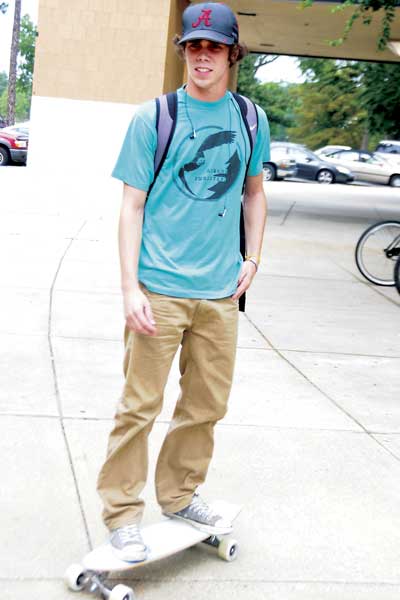 Skateboarder rolls leisurely to class.