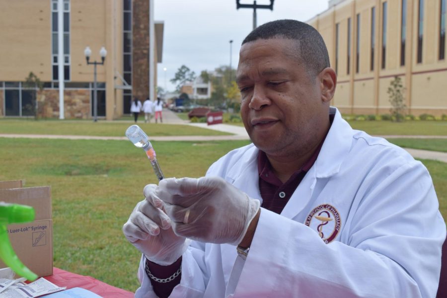 Dr. Anthony Walker prepares to give a flu shot in the Quad last semester.