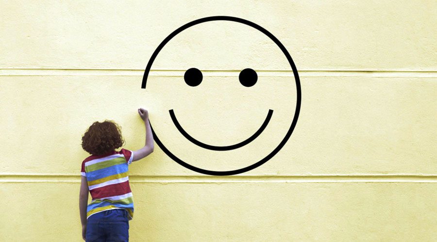 Girl drawing smiley face on to a wall