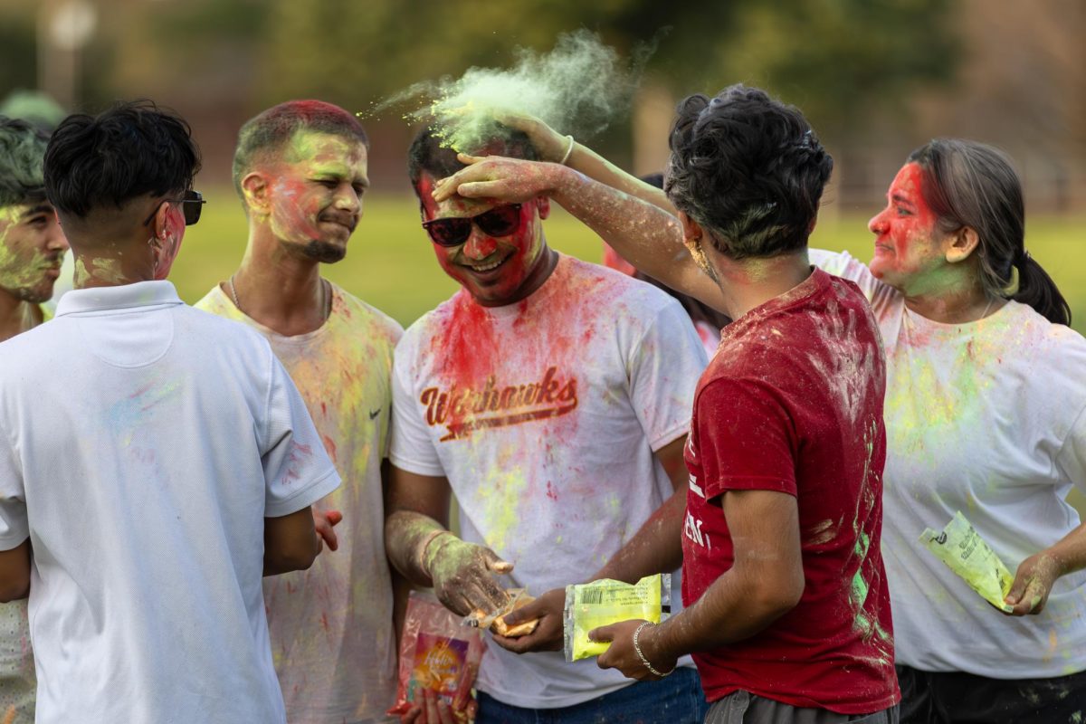 A group of students gather as yellow powder is showered over them during the Holi celebration hosted by the Nepalese Student Association (NSA).