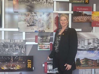 Picture of Cindy Foust in front of the university’s artistic timeline in the ULM Advancement, Foundation & Alumni Relations office.